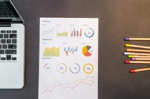Top view of charts and colored pencils on a desk next to a laptop, perfect for business or education themes.